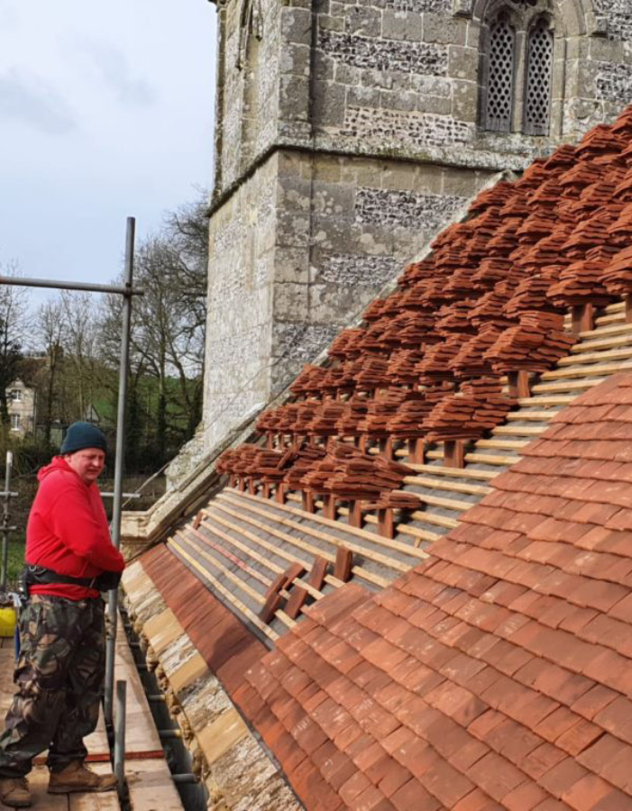 Master tiler working on church roof